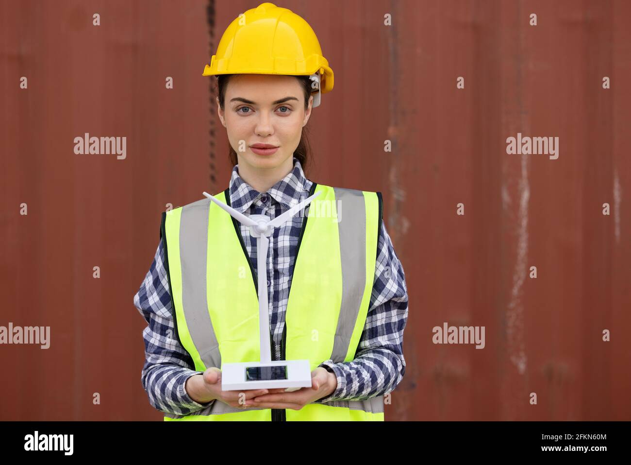 factory workers or engineers holding light bulb and using tablet computer with windmill model on solar panel,  work in containers warehouse storage Stock Photo