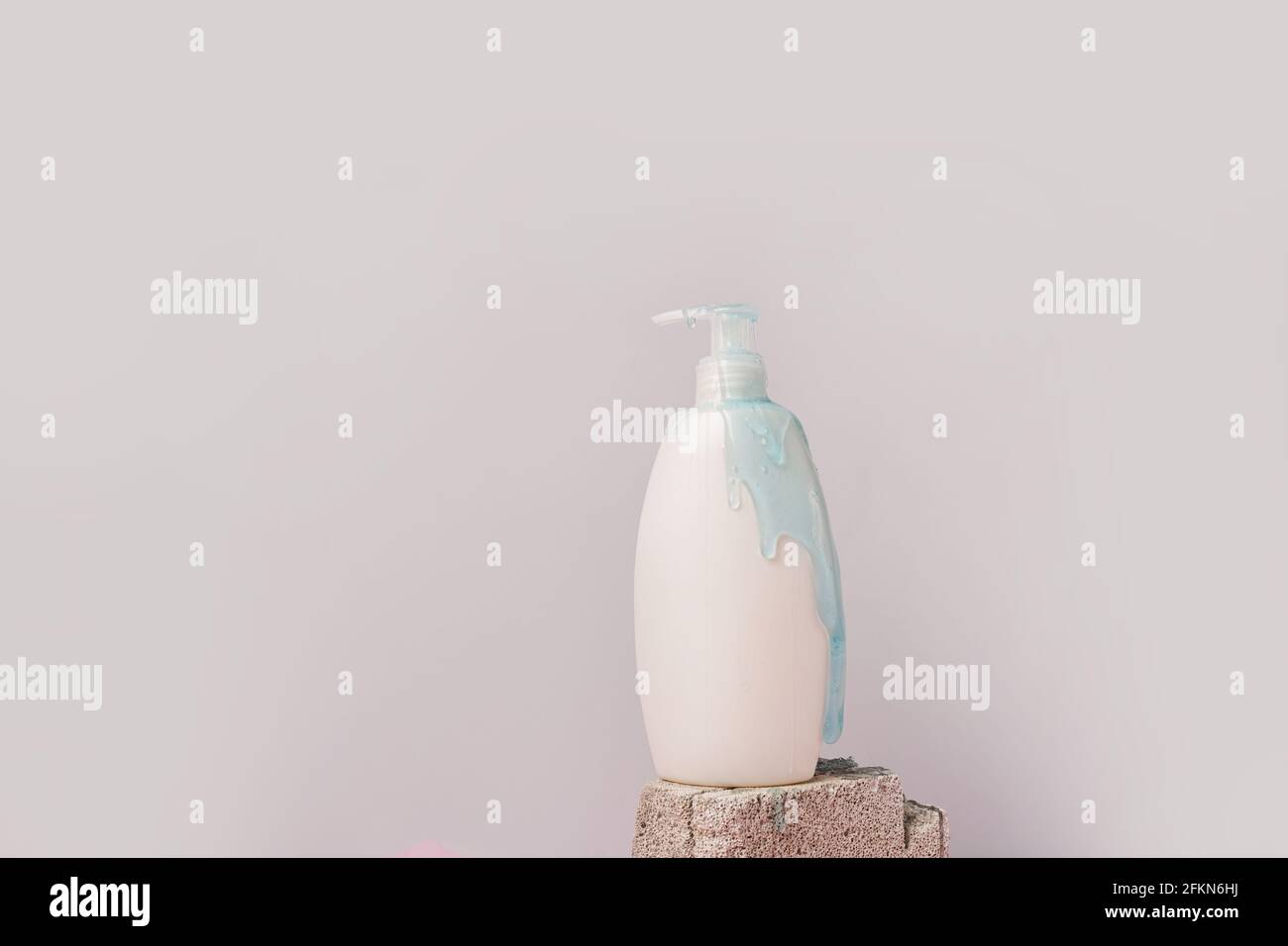 clean body lotion bottle with blue gel drops on the stone on gray