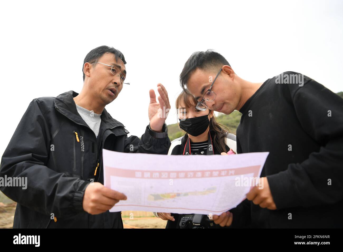 (210503) -- TIANSHUI, May 3, 2021 (Xinhua) -- Zhang Shuhao (1st L) discusses the construction plan for a production base with his colleagues in Mudan Township, Tianshui City of northwest China's Gansu Province, on April 27, 2021. Zhang Shuhao, 42, quit his well-paid job three years ago to start an agriculture company with a few partners sharing the same vision at a mountainous village in Mudan Township, Tianshui City. In three years, Xinghuarong, Zhang's company, contracted 6,200 mu (about 413 hectares) of idle arable lands, where terraced fields, greenhouses, and a reservoir have been built Stock Photo