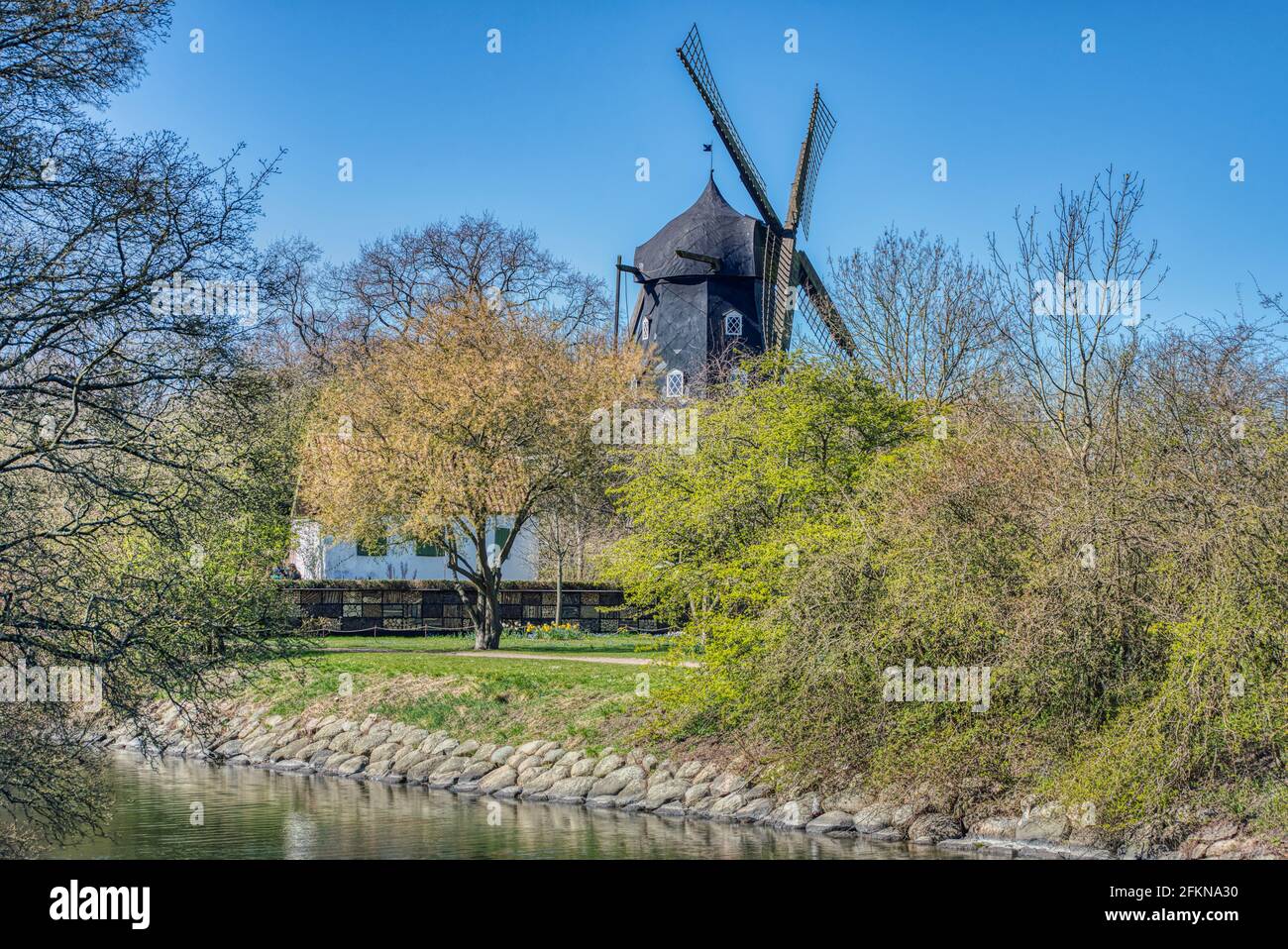 Slottsmollan (Castel wind mill) in the popular Malmo Kungsparken among blooming trees as the park 's canal flows underneath the wooden windmill Stock Photo