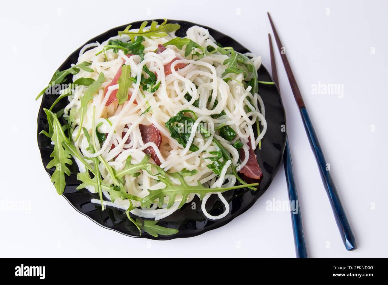 Pasta with prosciutto and arugula vegetable served on a plate Stock Photo