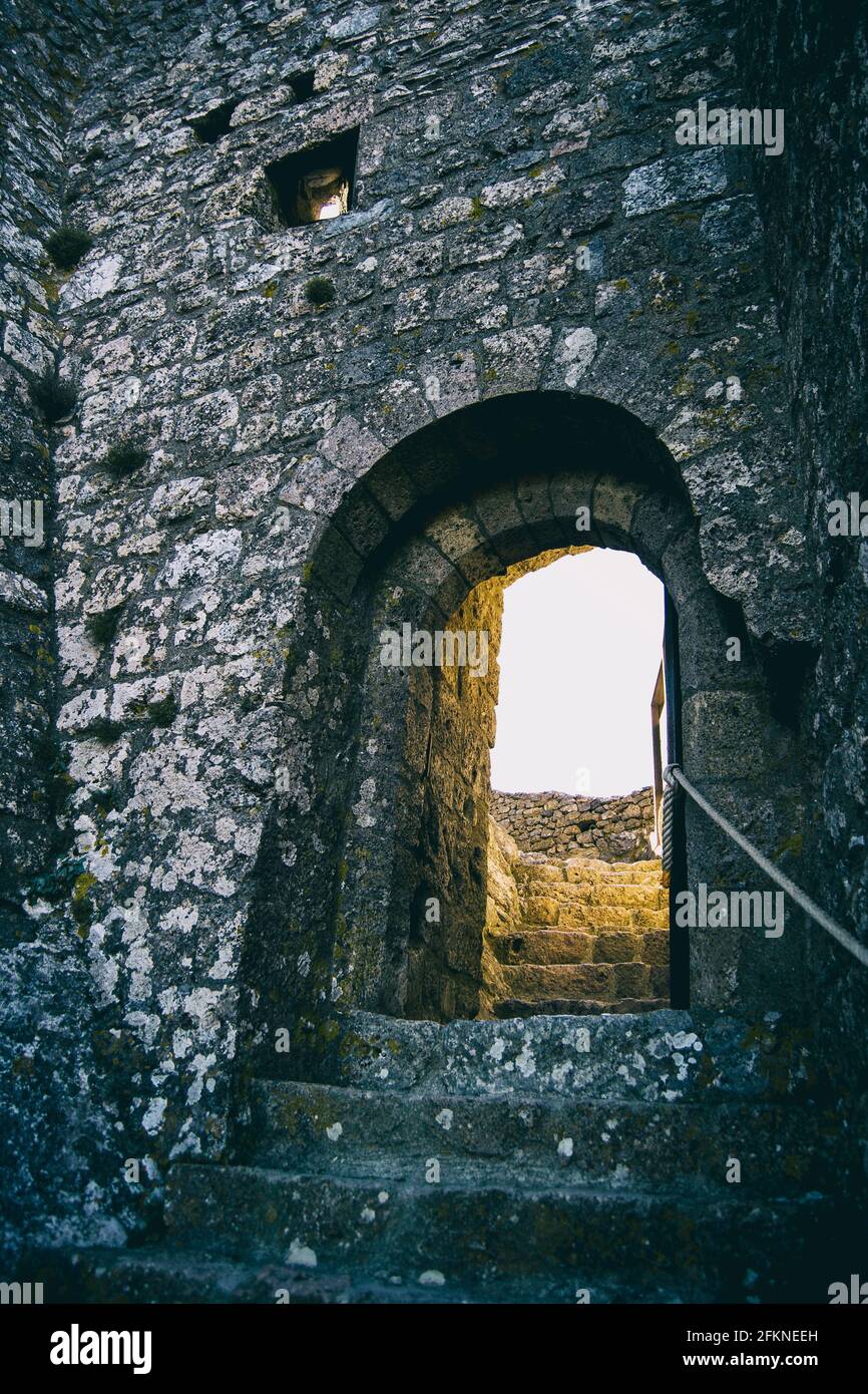 old stone stairs leading to a stone wall with an arch as a door Stock Photo