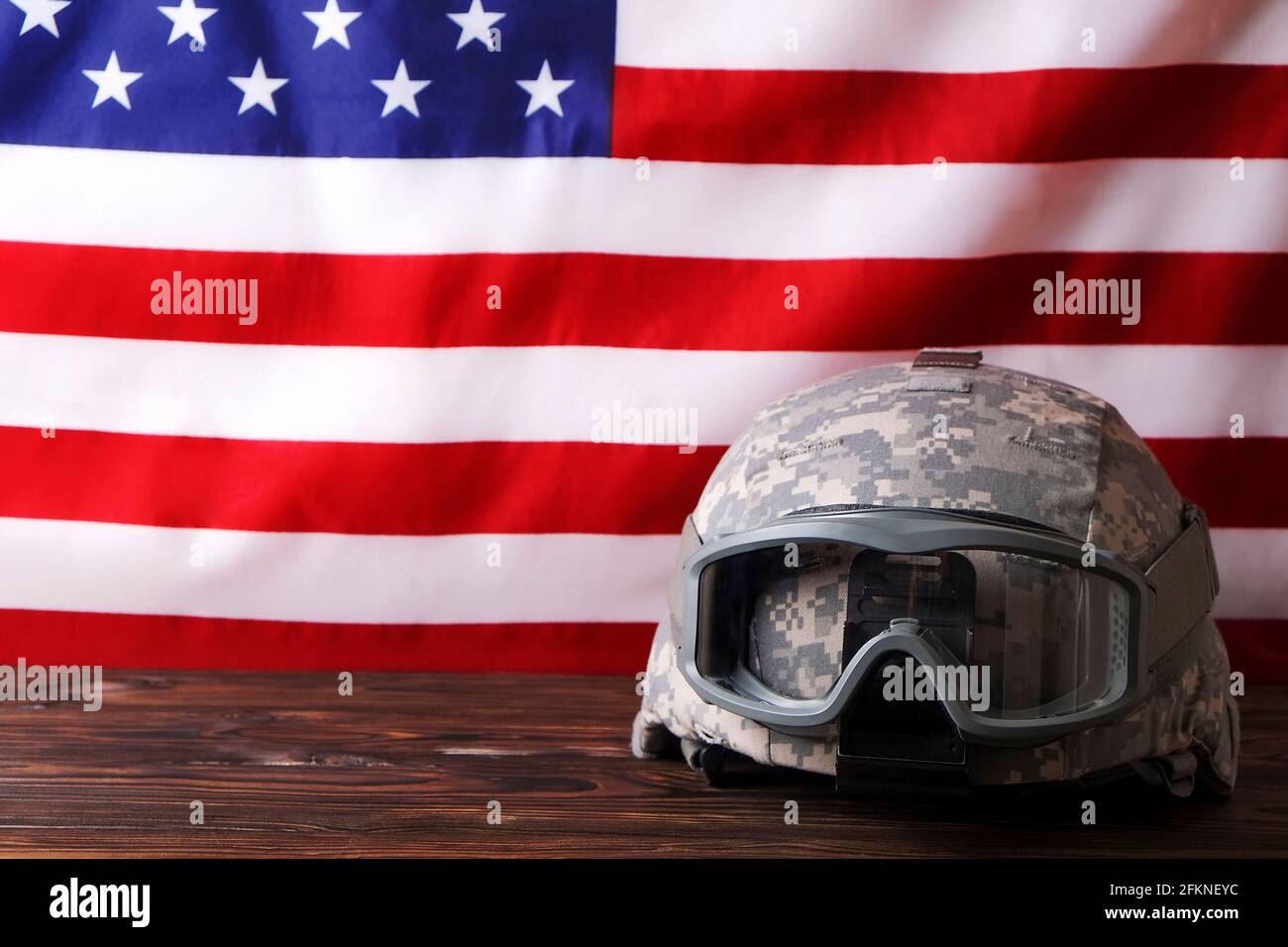 US Army kevlar combat helmet, camo cover, tactical goggles, USA flag background. Memorial weekend, veterans day, United States of America armed forces Stock Photo