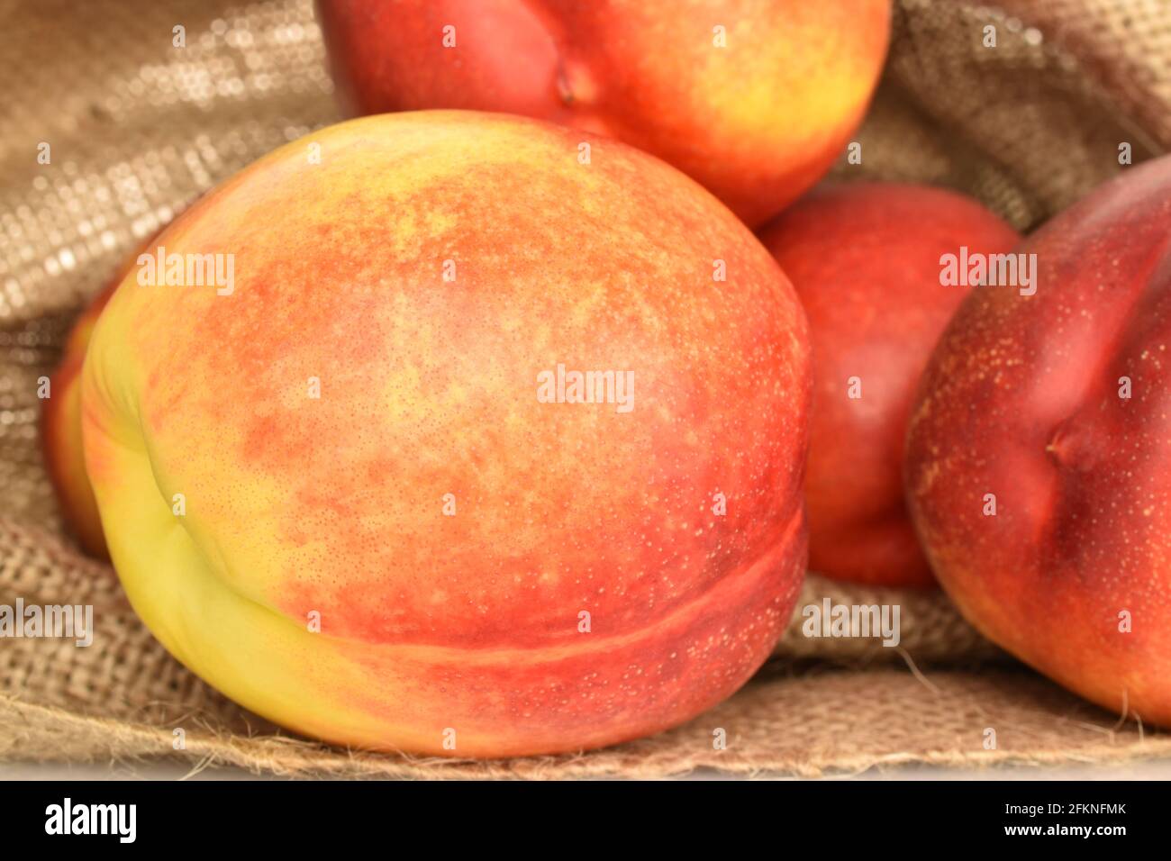 Several juicy organic nectarines in a jute bag, close-up. Stock Photo