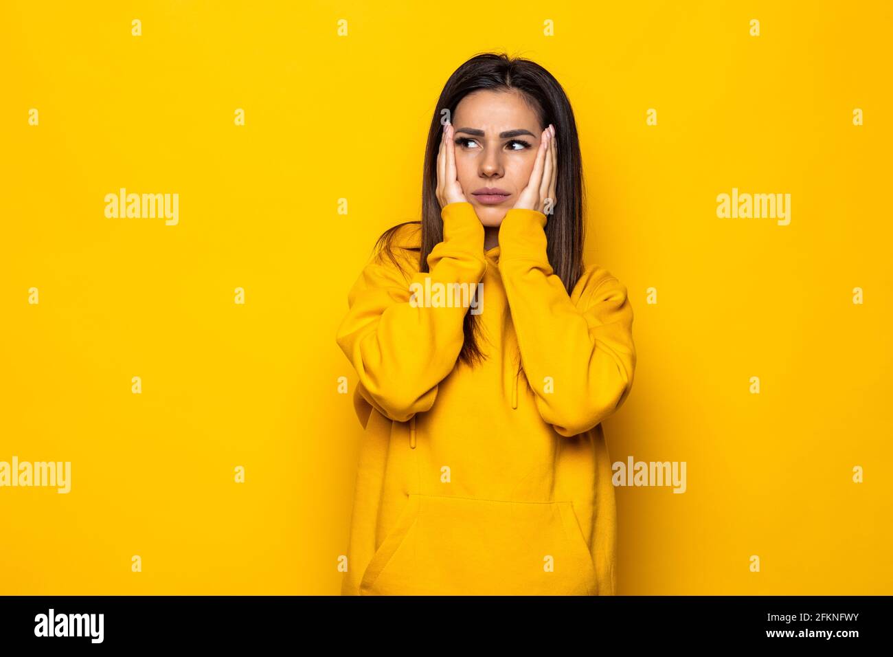Thinking woman looking up and around on yellow background Stock Photo ...