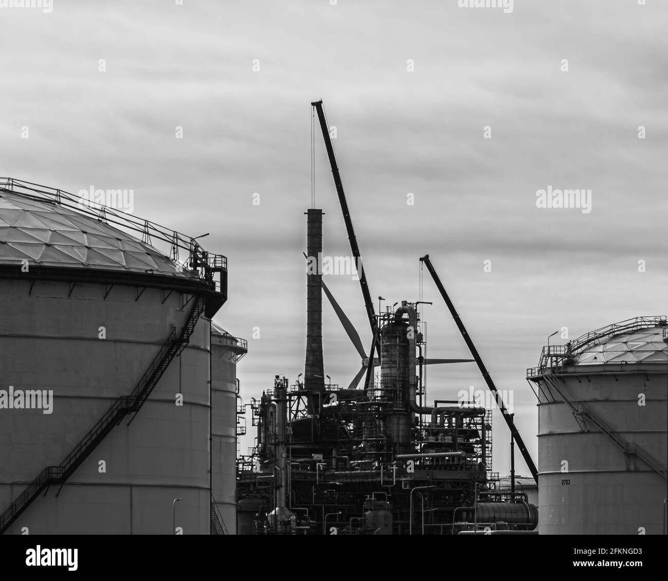 Closeup of giant storage tanks with an industrial machines and windmill behind it Stock Photo