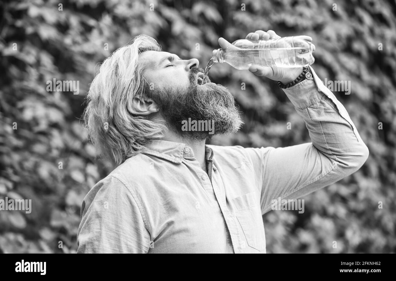 Another sip. Handsome Man Drinking Fresh Water From bottle. Morning routine. Daily intake of water. Thirsty male model enjoying refreshing drink Stock Photo