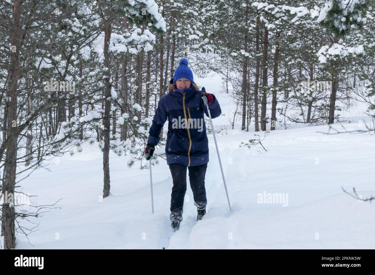 Elderly retired baby boomer senior woman during outdoor physical activities in woodland at snowy winter day. Active lifestyle in senior age Elderly wo Stock Photo