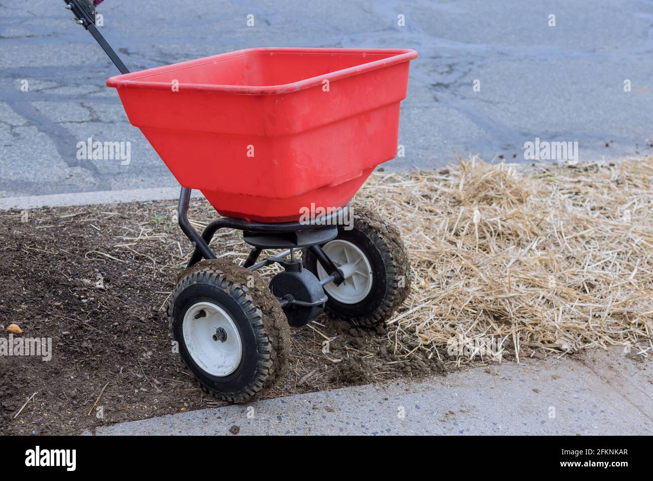Landscaping work sowing lawn grass seeds with a drop lawn spreader in the residential backyard