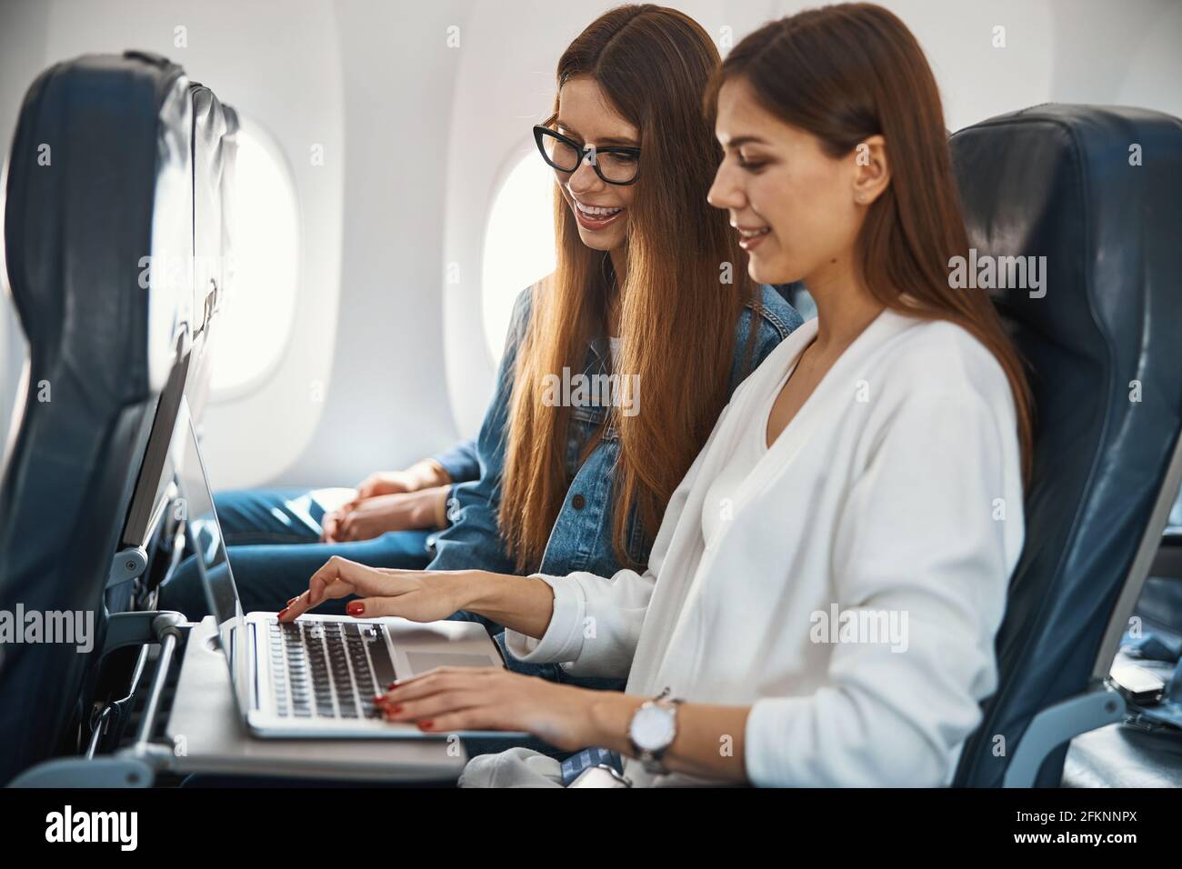 Two gladsome ladies using laptop in the plane Stock Photo Alamy