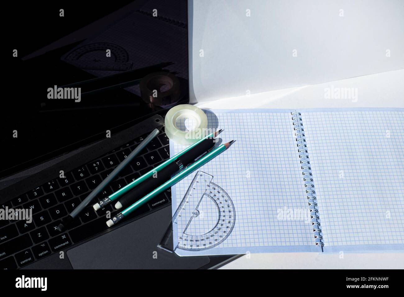Office supplies and square shape notebook on laptop keyboard. Template for corporate student and school design. Stock Photo