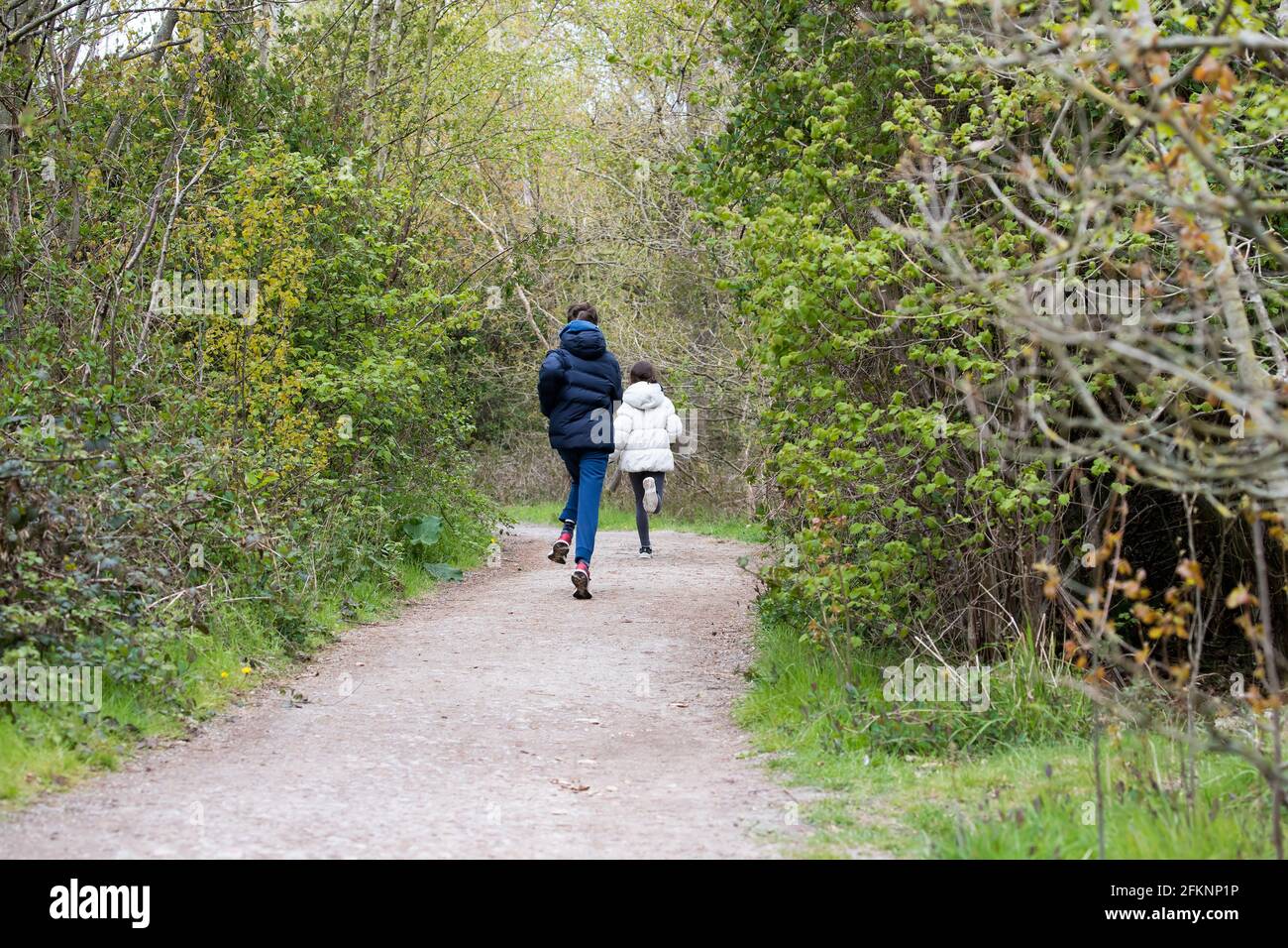 A young boy and girl enjoying a day out running down a tree lined path at RSPB Fairburn Ings, Nature Reserve,Yorkshire U.K. Stock Photo