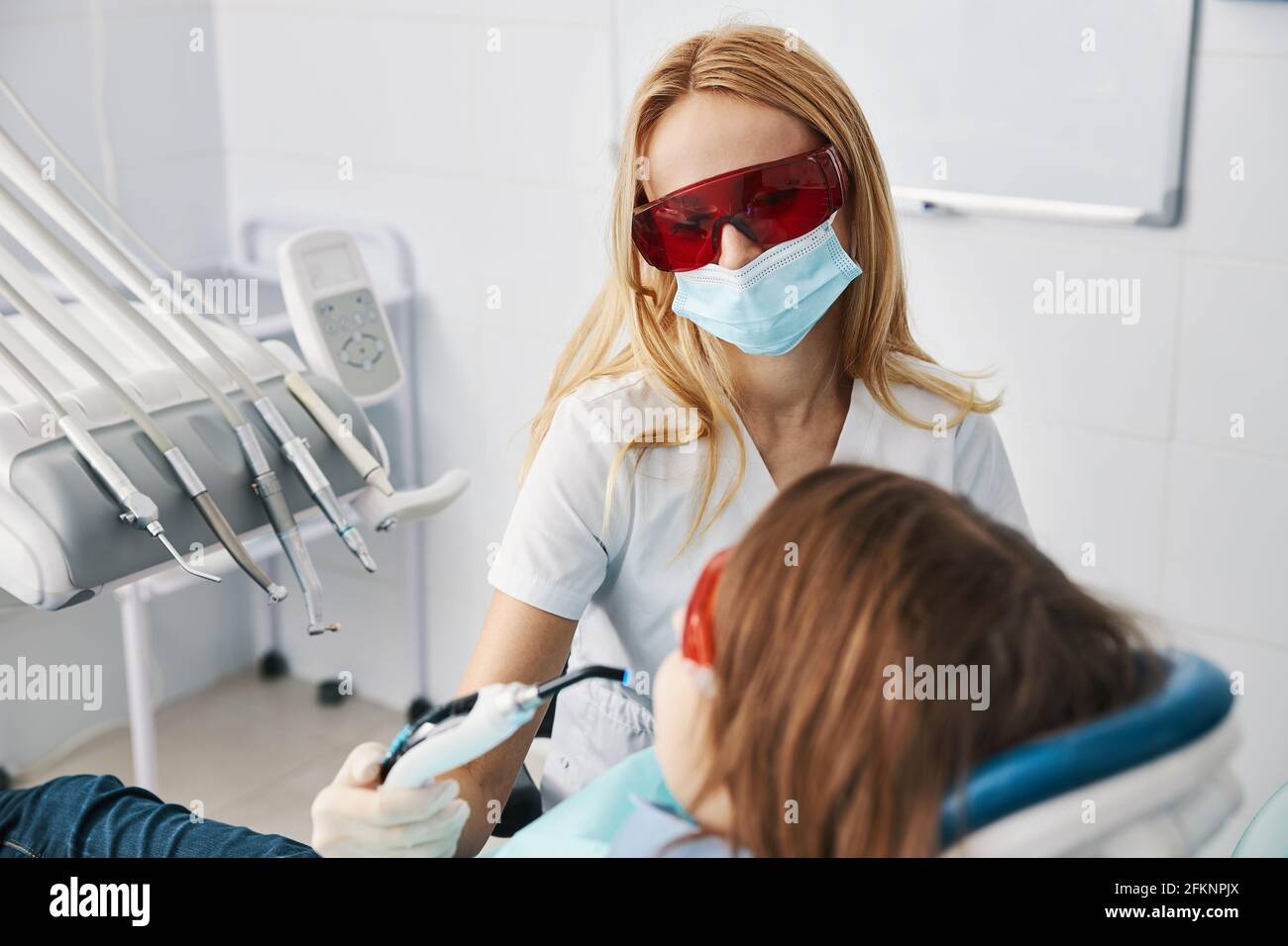 Woman medic setting composite fillings with dental curing lights Stock