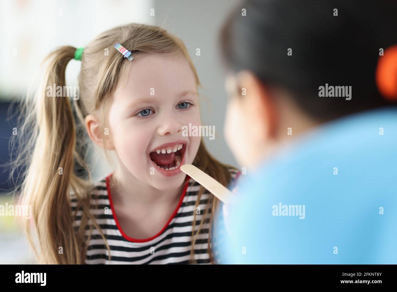 Otorhinolaryngologist doctor examining sore throat little girl in
