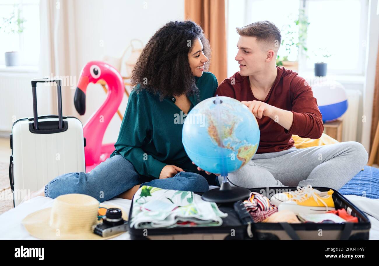 Young couple with map packing for holiday at home, new normal. Stock Photo