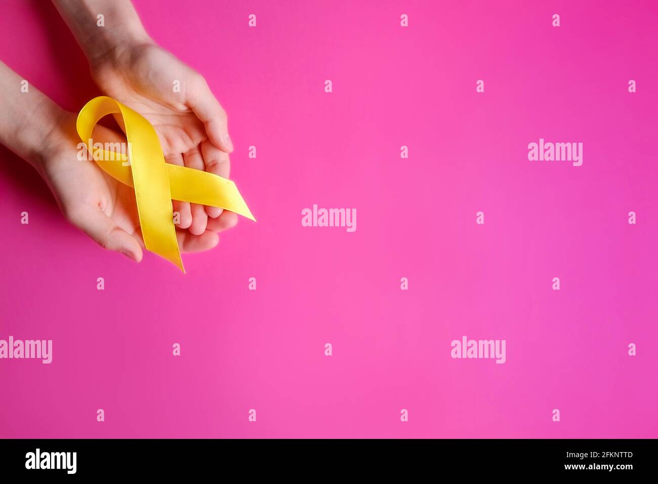 Woman's hand holding yellow ribbon - bladder, liver and bone cancer awareness symbol. Children cancer prevention concept. Isolated background, copy sp Stock Photo