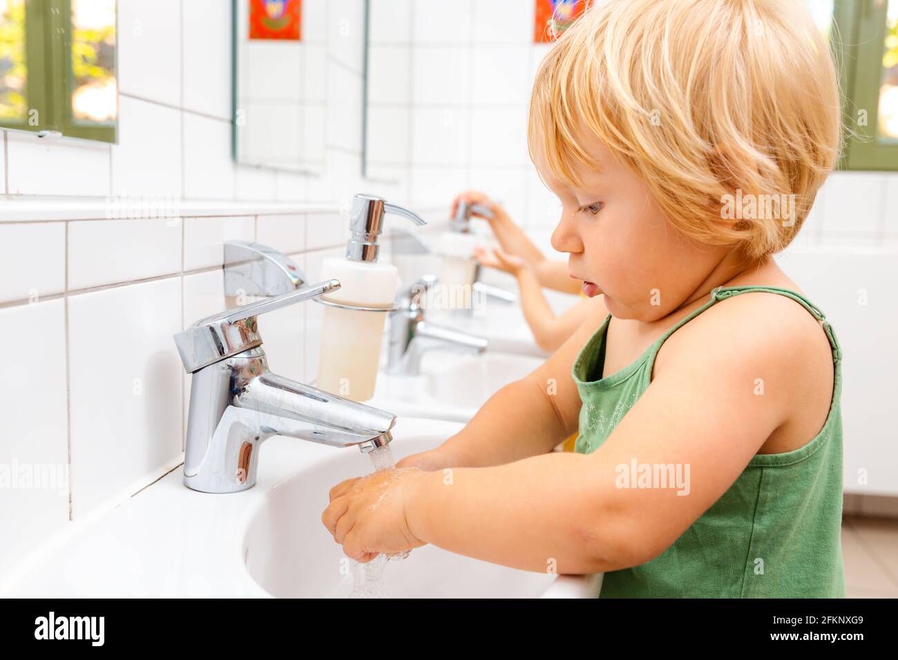 Child in kindergarten washing her hands Stock Photo