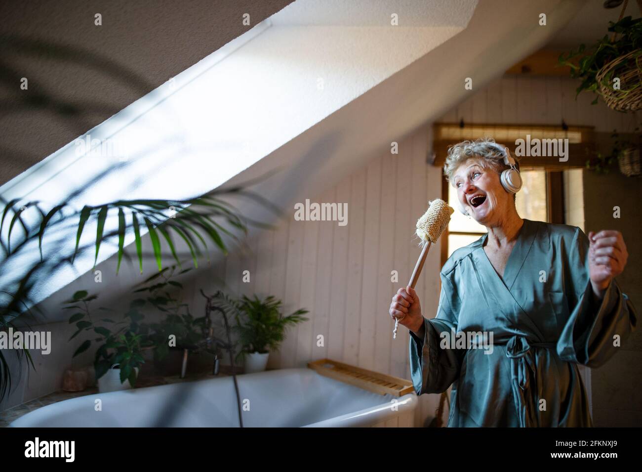 Happy senior woman with headphones singing at home, relax and self-care concept. Stock Photo