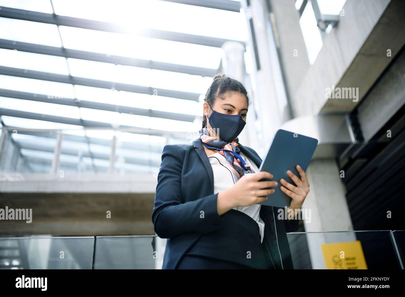 Young air hostess with tablet in airport lounge, coronavirus, travel and new normal. Stock Photo