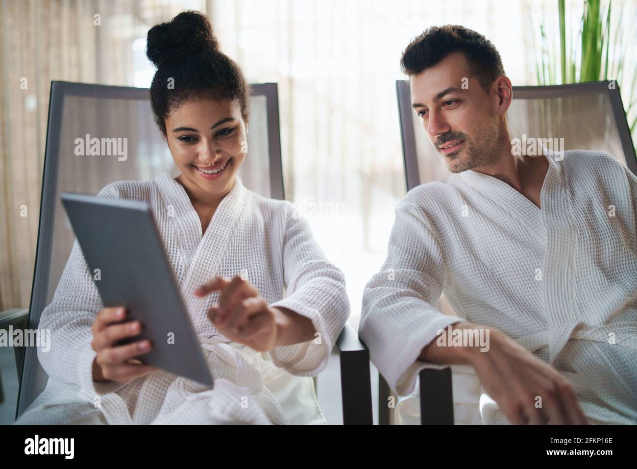 Portrait of young couple relaxing in spa resort, using tablet. Stock Photo
