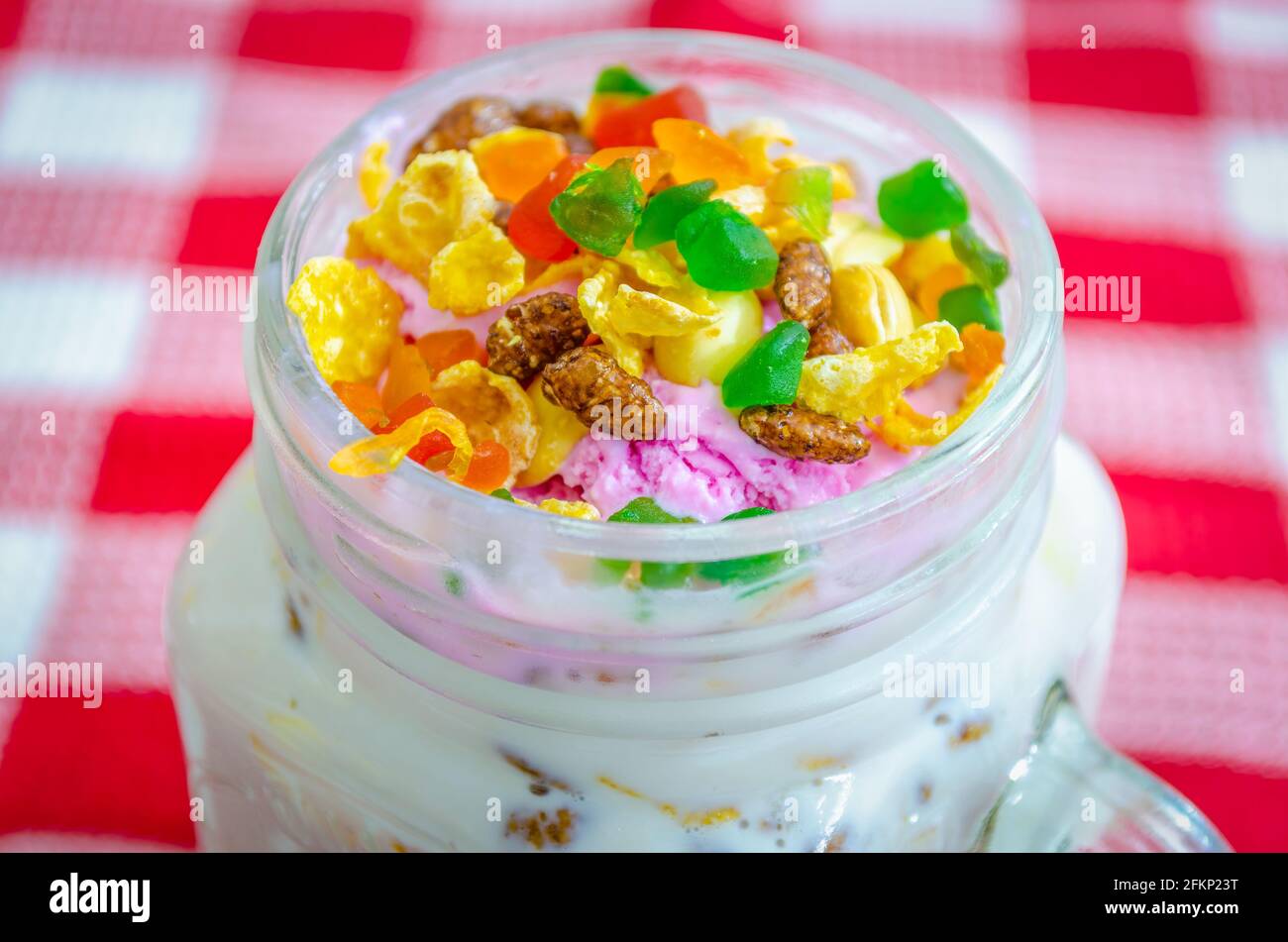 Colorful Tutti Frutti and dry fruits on strawberry ice cream milkshake in a tumbler Stock Photo