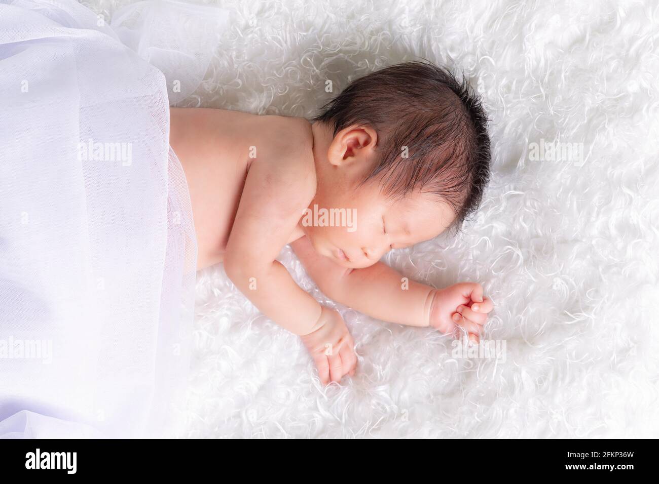 Portrait of a one month old sleeping, newborn baby girl on a white blanket. Concept portrait studio fashion newborn. Stock Photo