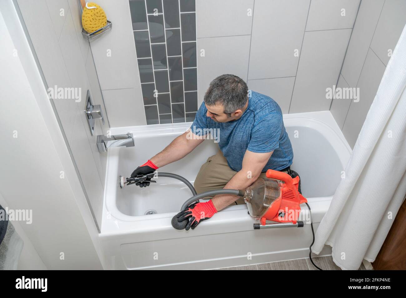 https://c8.alamy.com/comp/2FKP4NE/plumber-drain-cleaning-a-bathtub-with-a-plumbers-snake-2FKP4NE.jpg