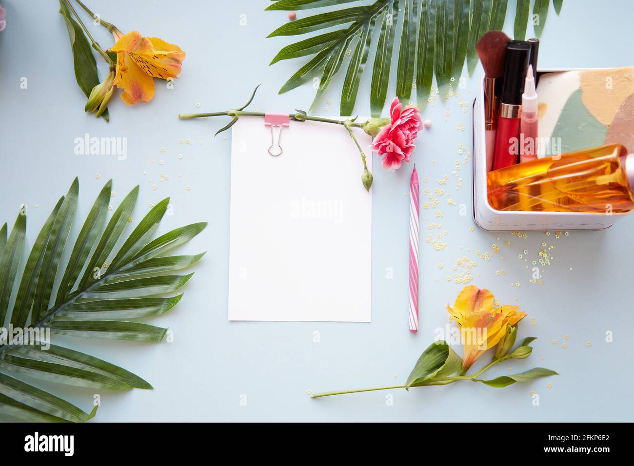 Summer beauty concept background with stationery card, pen, tropical leaves, cosmetic products and alstroemeria flowers. High quality photo Stock Photo