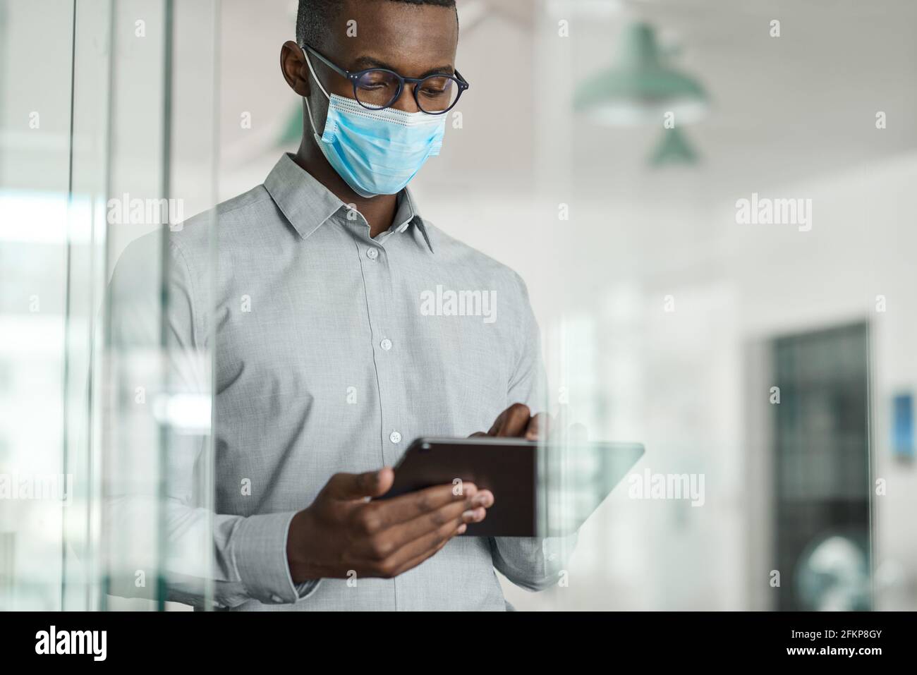 African businessman wearing a face mask using a digital tablet Stock Photo