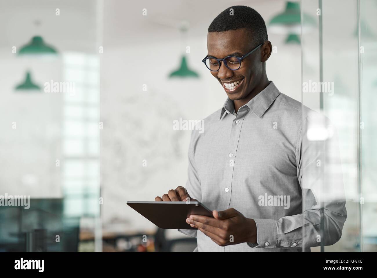 Smiling young African businessman using a digital tablet at work Stock Photo