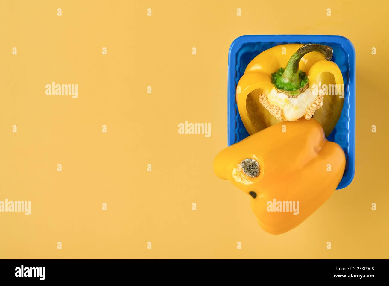Moldy and wrinkled rotten yellow peppers. Concept of unhealthy, decompose, spoiled vegetables. Garbage dump rotten food on yellow background. Top view Stock Photo