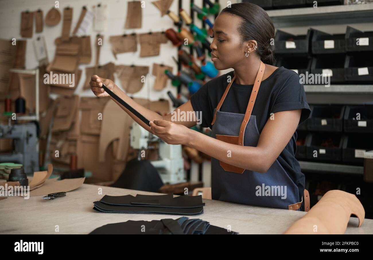 Young African female artisan working in her leather studio Stock Photo
