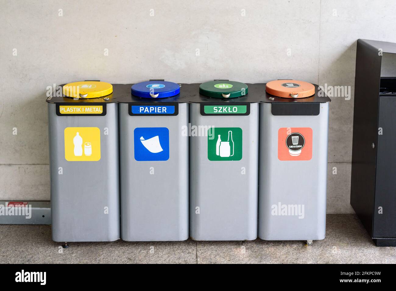 Waste containers for garbage segregation in Poland, standing next to a wall Stock Photo