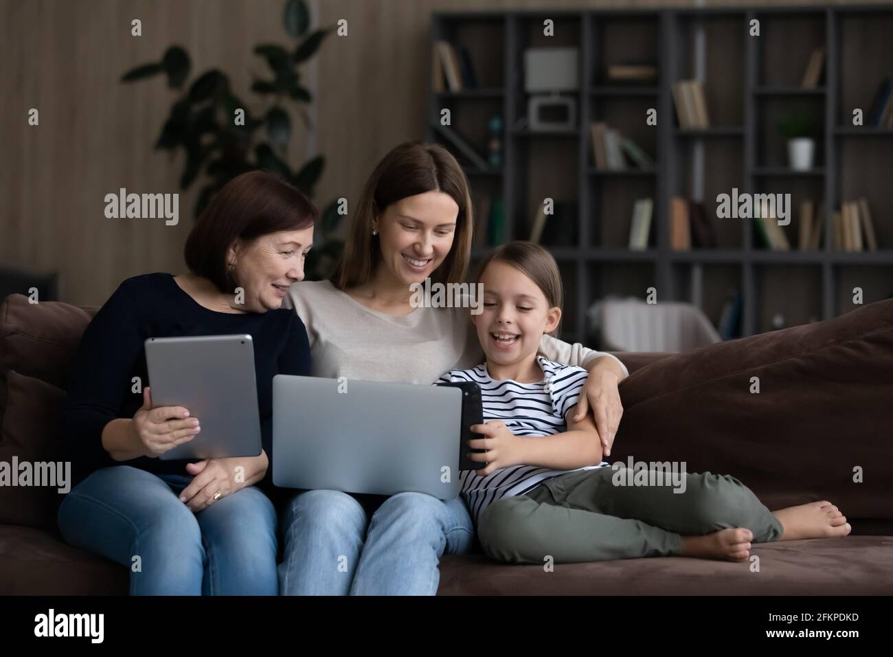 Happy three generations of women relax using gadgets Stock Photo