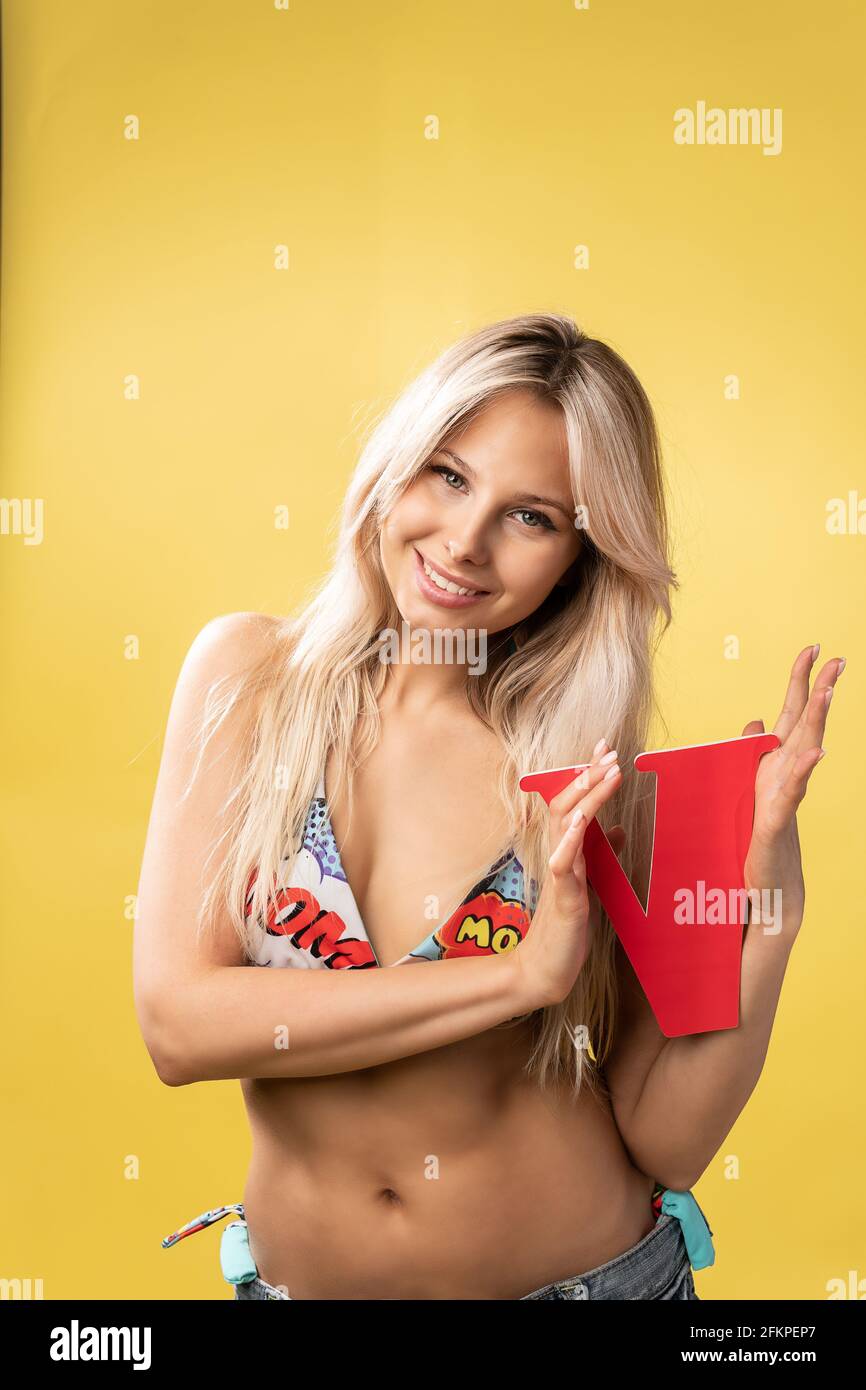 Girl holds the letters of the alphabet word love on a yellow background blonde beautiful smiles abc concept background, one young student smile, kid Stock Photo