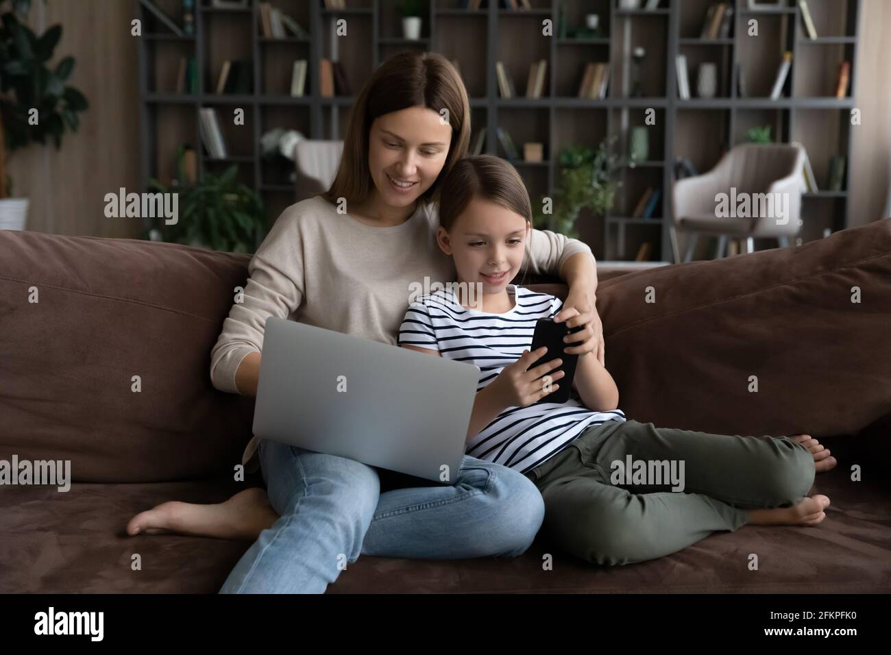 Young mom and small daughter relax using devices Stock Photo - Alamy