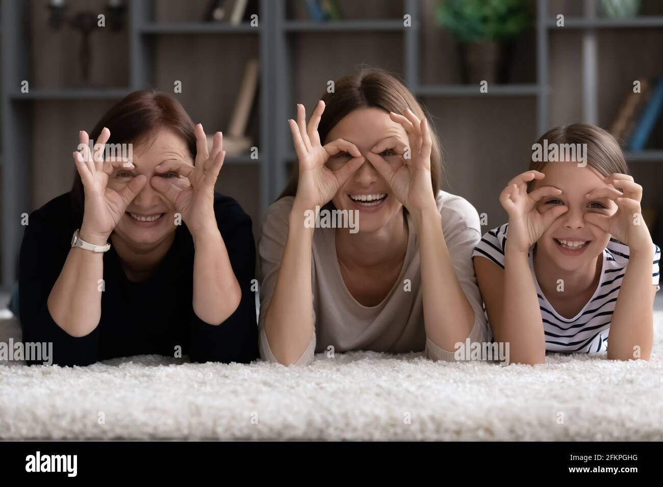 Portrait of three generations of women make glasses with fingers Stock Photo