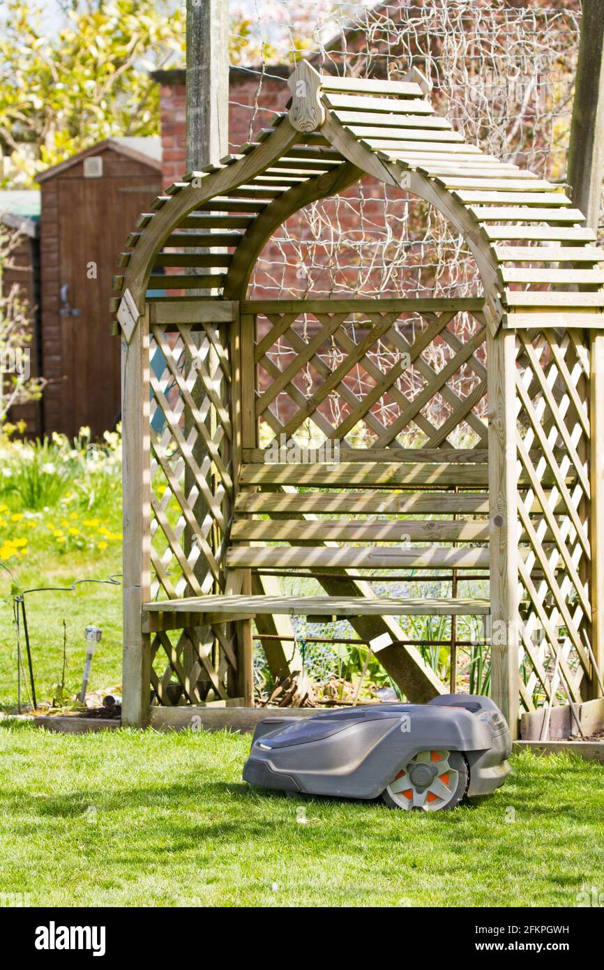 Husqvarna robotic robot  automatic lawn mower in use in an English country garden mowing and cutting  a grass lawn Stock Photo
