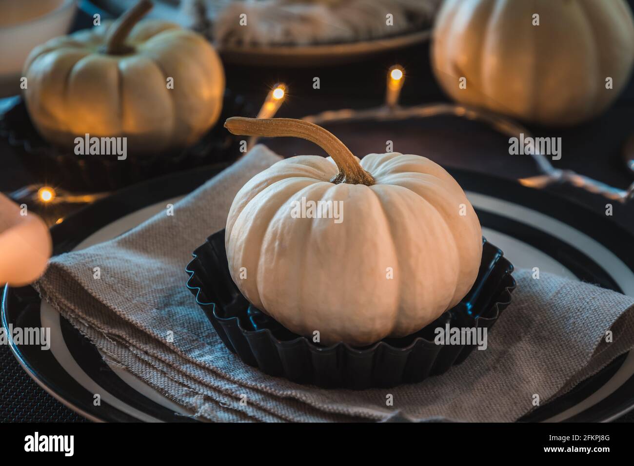 Place setting with a white mini pumpkin on a black and white decorated eating table Stock Photo