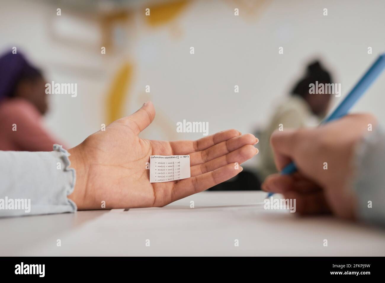 Close up of unrecognizable female student hiding cheat note while taking exam in school, copy space Stock Photo