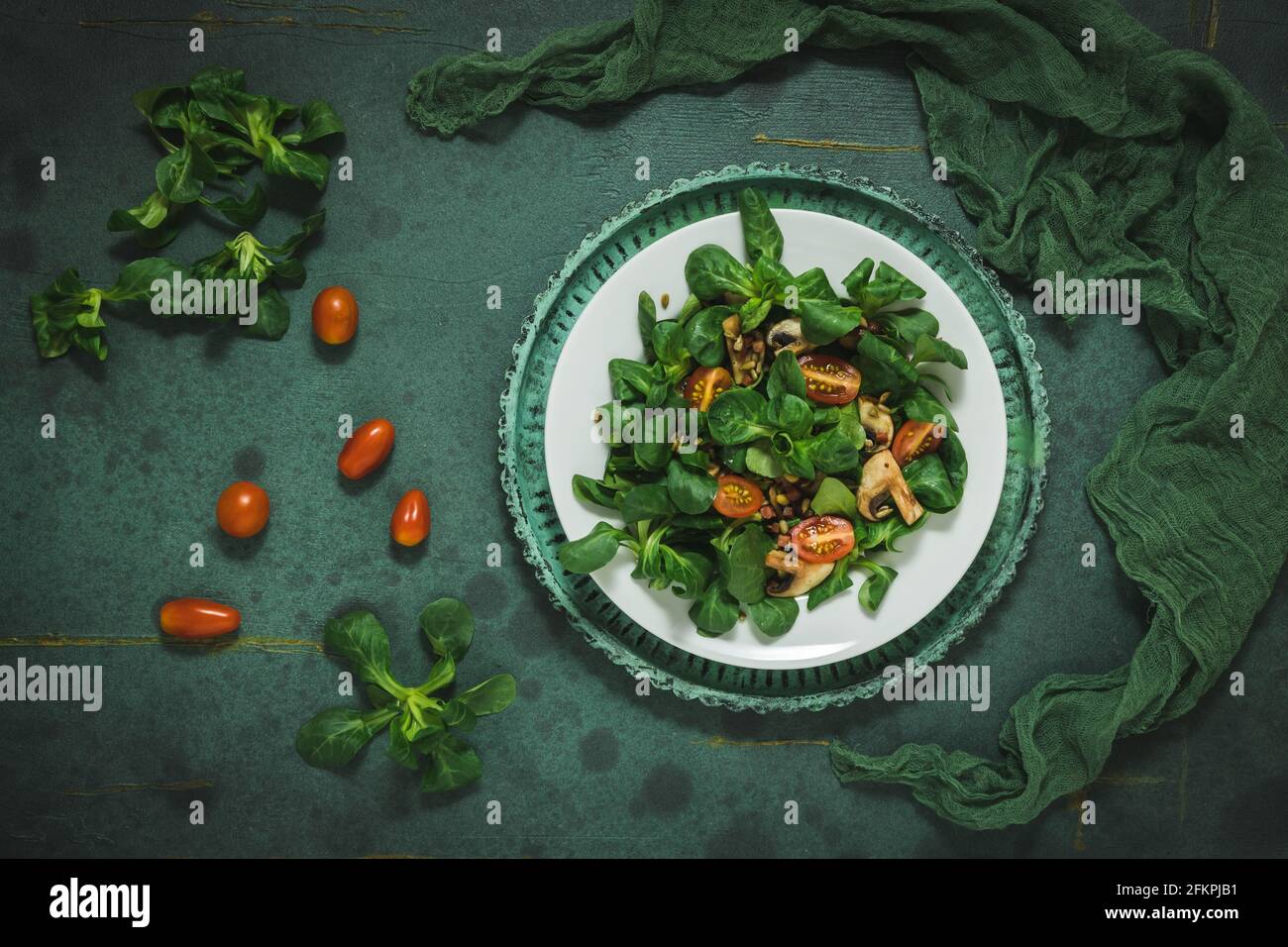 Fresh corn salad with mushrooms and roasted seeds on a white plate on green background, top view Stock Photo