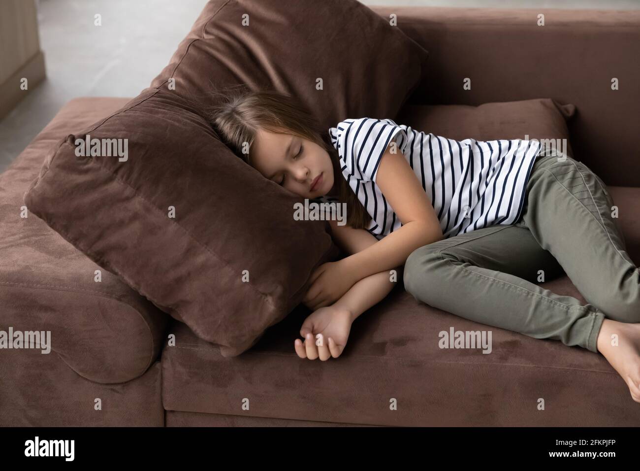 Tired small girl child sleep on sofa at home Stock Photo