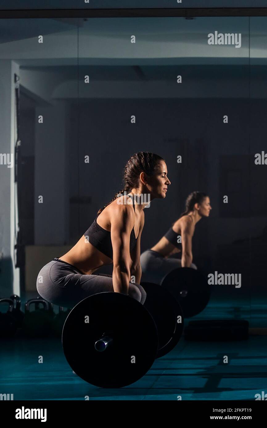A female training and simultaneously doing dead-lift exercise at the gym. Stock Photo