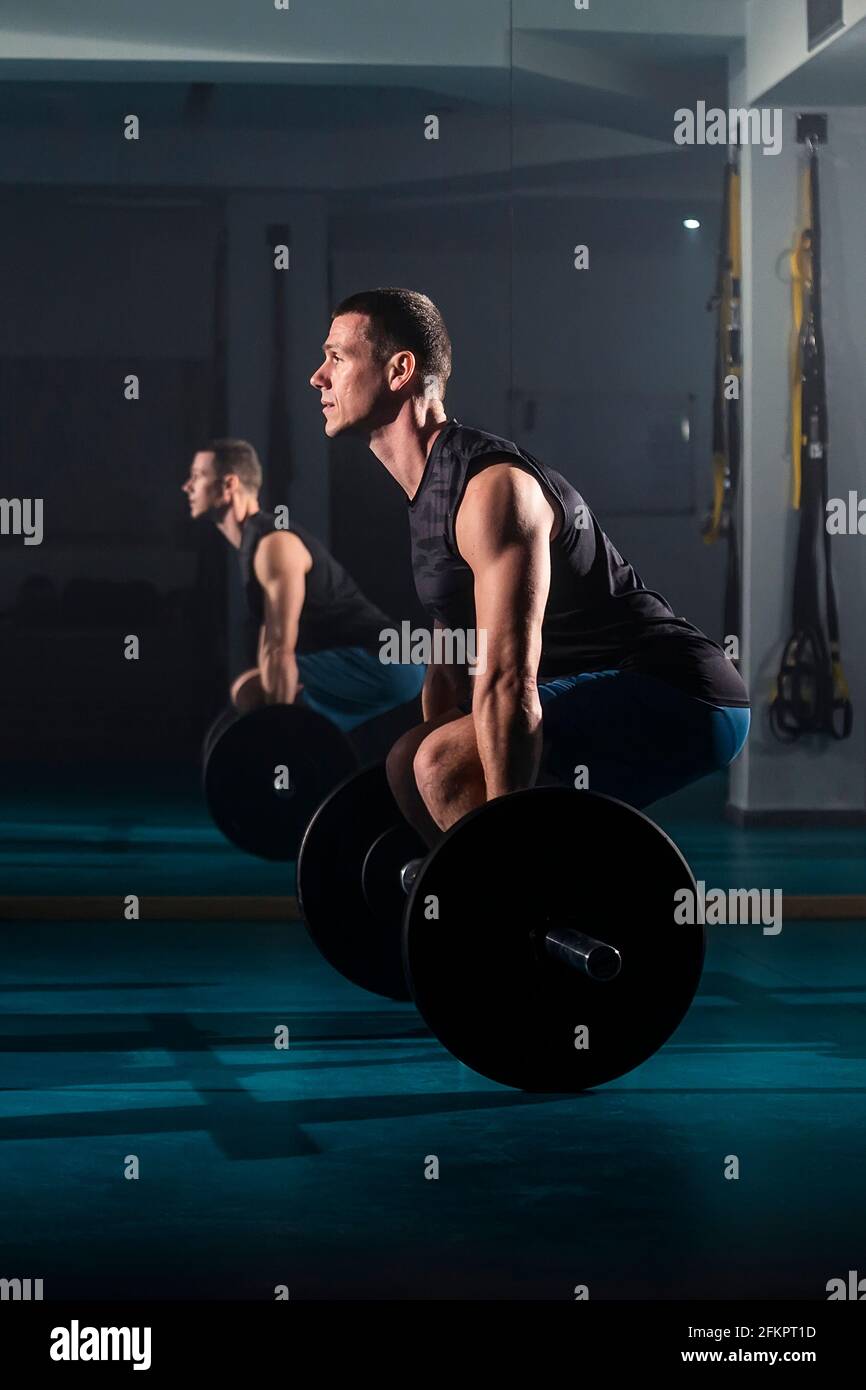 A man training and simultaneously doing dead-lift exercise at the gym. Stock Photo