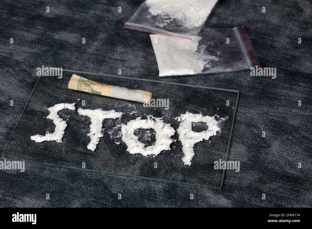 Line of white powder drugs, Cocaine, speed and plastic bags with other drugs, STOP written in the powder, Addiction,drug,junky,dealer concept Stock Photo
