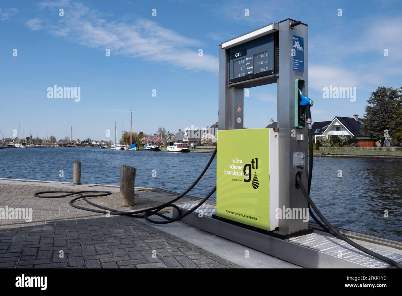Gas station for clean fuel unleaded 98 gasoline along the waterfront with moored boats in the harbor with cityscape of Lemmer, Netherlands Stock Photo