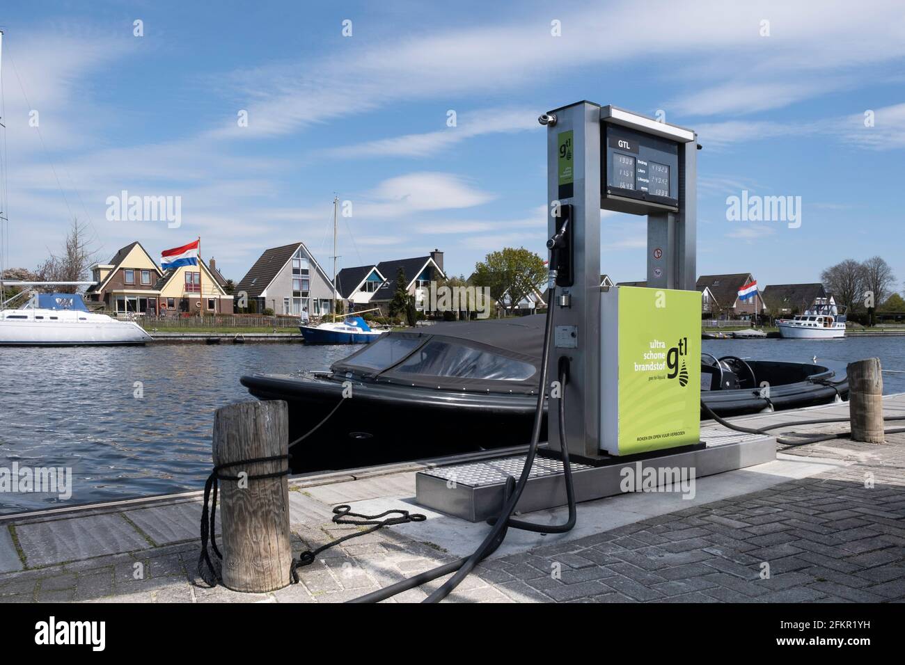 Gas station for clean fuel unleaded 98 gasoline along the waterfront with moored boats in the harbor with cityscape of Lemmer, Netherlands Stock Photo