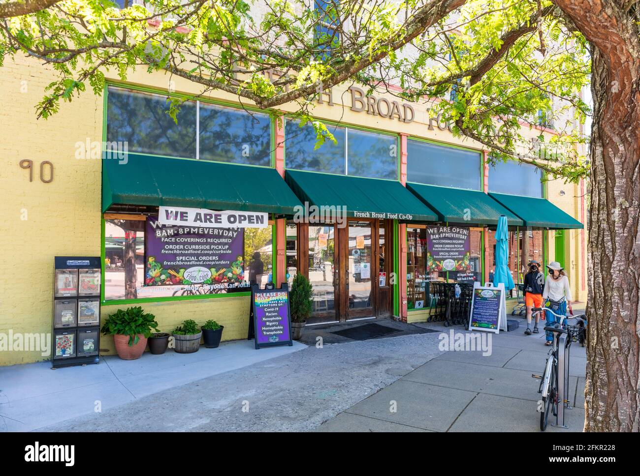 ASHEVILLE, NC, USA-1 MAY 2021: Front view of the French Broad Food Co-Op, sunny spring day.  A male-female couple walking by. Stock Photo