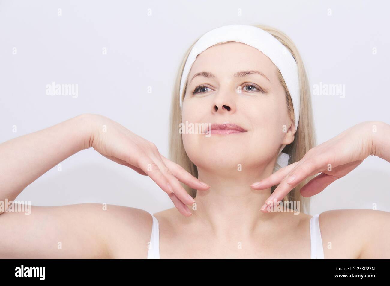 beautiful middleaged woman makes selfmassage of the face, exercise to