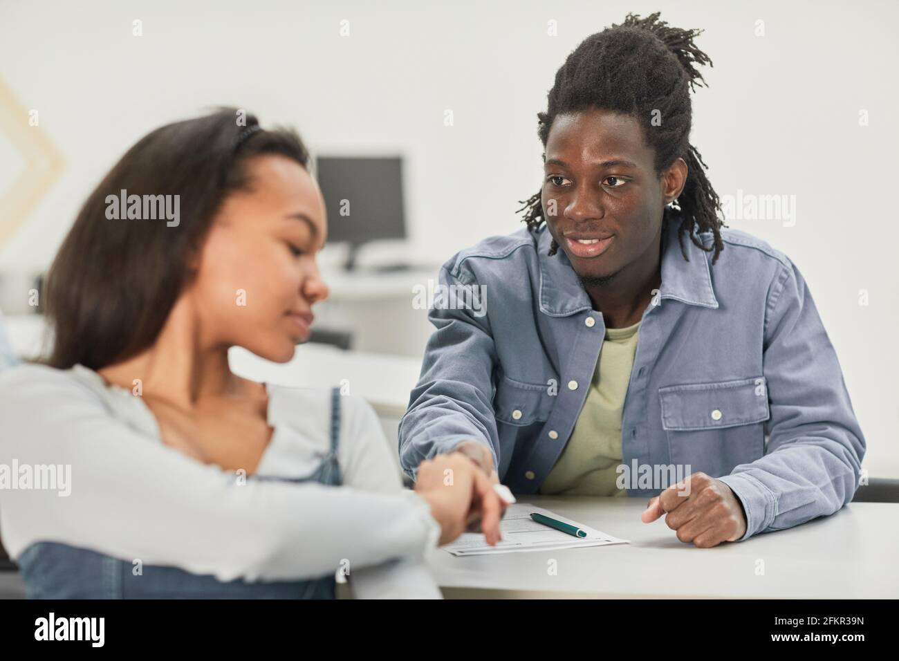 Portrait of two African-American students passing notes during class in school, copy space Stock Photo